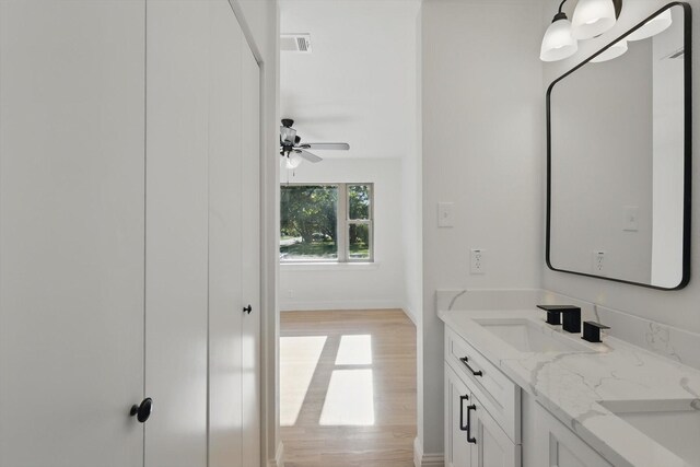 10626 Desdemona Dr, Dallas, TX 75228 - bathroom featuring double vanity, wood finished floors, baseboards, and ceiling fan
