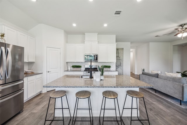 6217 Cheshire St, Celina, TX 76227 - kitchen with stainless steel appliances, a kitchen breakfast bar, open floor plan, white cabinets, and recessed lighting