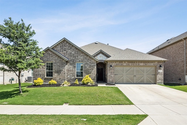 6217 Cheshire St, Celina, TX 76227 - french country home featuring concrete driveway, a front lawn, an attached garage, brick siding, and roof with shingles
