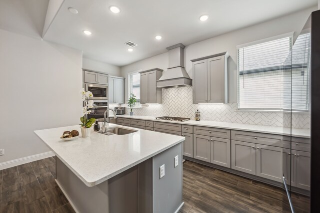 2811 Trinity Ridge St, Mansfield, TX 76063 - kitchen with gray cabinetry, custom range hood, a sink, appliances with stainless steel finishes, and decorative backsplash