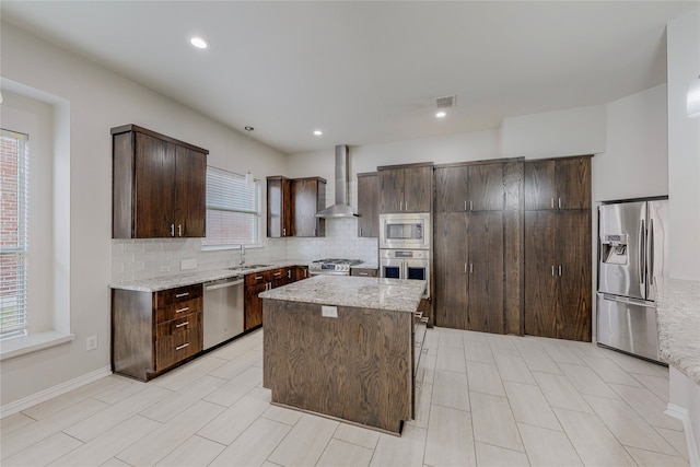 2728 Gull Lake Dr, Plano, TX 75025 - kitchen featuring appliances with stainless steel finishes, wall chimney exhaust hood, a sink, dark brown cabinetry, and decorative backsplash