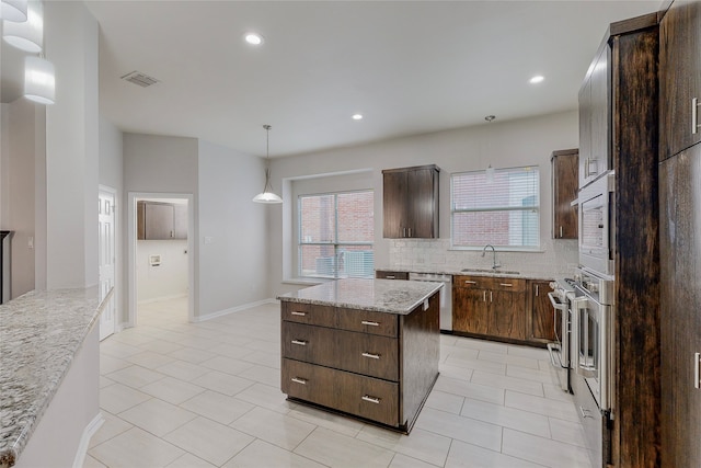 2728 Gull Lake Dr, Plano, TX 75025 - kitchen with appliances with stainless steel finishes, a center island, backsplash, light tile patterned floors, and dark brown cabinets