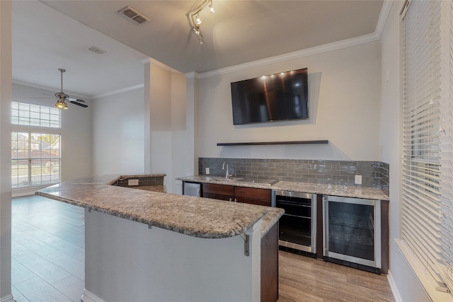 2728 Gull Lake Dr, Plano, TX 75025 - kitchen featuring wine cooler, a breakfast bar area, light wood finished floors, decorative backsplash, and ornamental molding