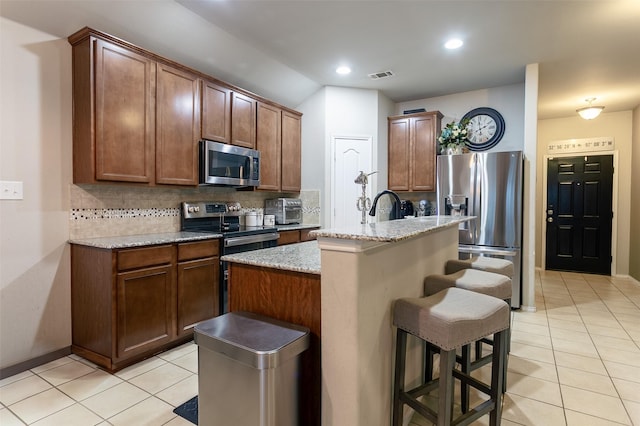 4633 Sleepy Meadows Dr, Fort Worth, TX 76244 - kitchen featuring stainless steel appliances, light tile patterned flooring, tasteful backsplash, a kitchen breakfast bar, and a kitchen island with sink