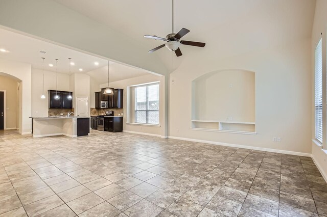 597 W Fate Main Pl, Fate, TX 75087 - kitchen featuring appliances with stainless steel finishes, a center island with sink, arched walkways, light stone countertops, and ceiling fan
