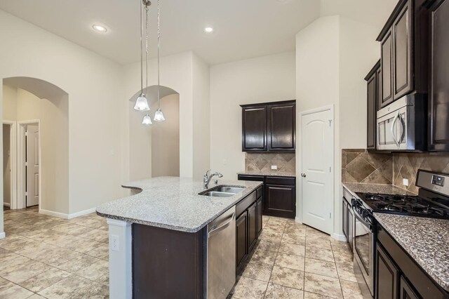597 W Fate Main Pl, Fate, TX 75087 - kitchen with stainless steel appliances, a kitchen island with sink, vaulted ceiling, decorative light fixtures, and light stone countertops