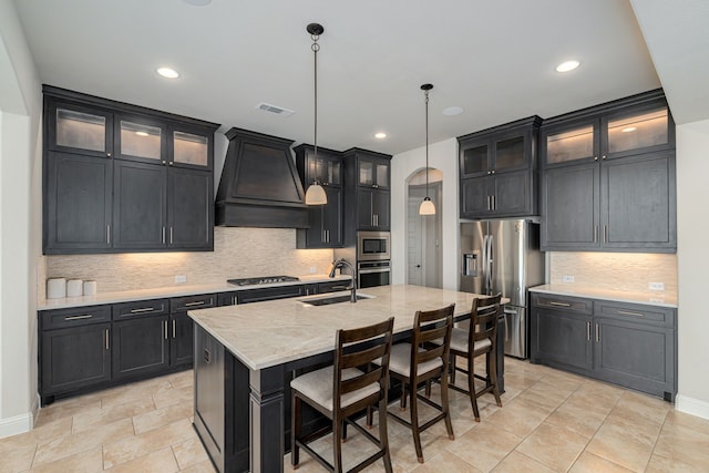 8220 Stonewall Dr, Waxahachie, TX 75167 - kitchen featuring stainless steel appliances, custom exhaust hood, a sink, decorative backsplash, and a kitchen island with sink
