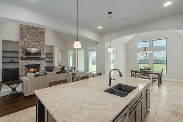 8220 Stonewall Dr, Waxahachie, TX 75167 - kitchen featuring a sink, built in shelves, light stone countertops, decorative light fixtures, and high vaulted ceiling