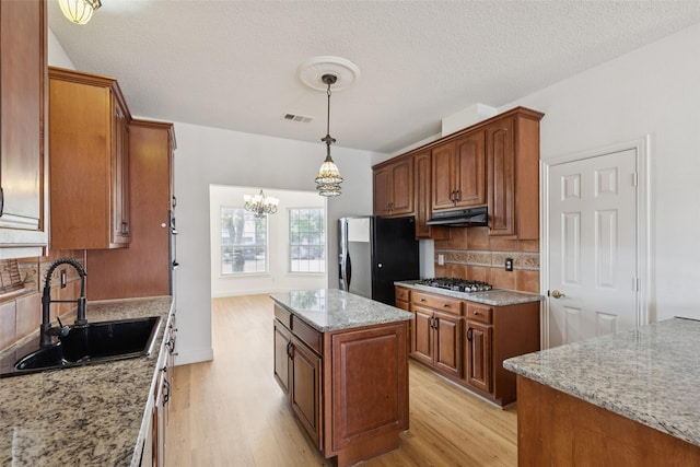 1084 Leisure Ln, Irving, TX 75063 - kitchen featuring fridge with ice dispenser, under cabinet range hood, light wood finished floors, tasteful backsplash, and a chandelier