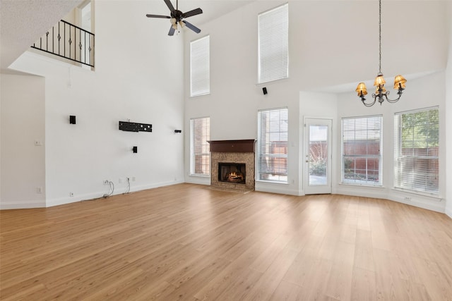 1084 Leisure Ln, Irving, TX 75063 - unfurnished living room featuring a high ceiling, a chandelier, light wood-style flooring, a ceiling fan, and a fireplace with flush hearth