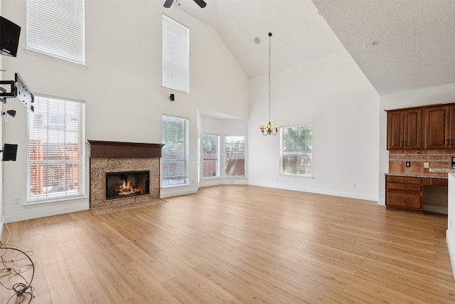 1084 Leisure Ln, Irving, TX 75063 - unfurnished living room featuring high vaulted ceiling, ceiling fan, light wood-style flooring, a premium fireplace, and a chandelier