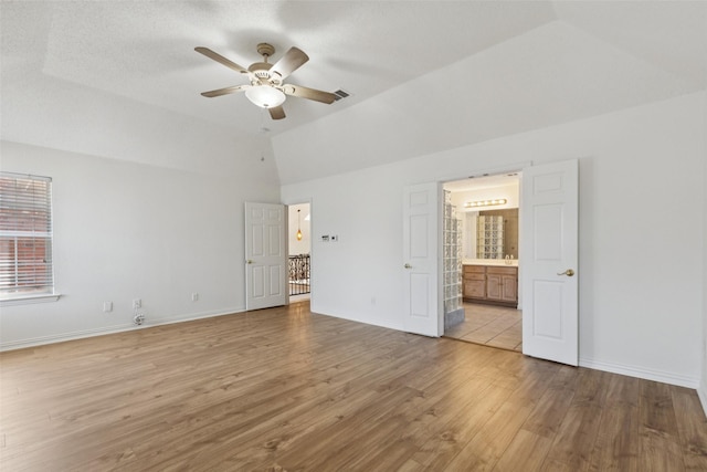 1084 Leisure Ln, Irving, TX 75063 - unfurnished bedroom featuring vaulted ceiling, light wood-style floors, ensuite bath, and ceiling fan