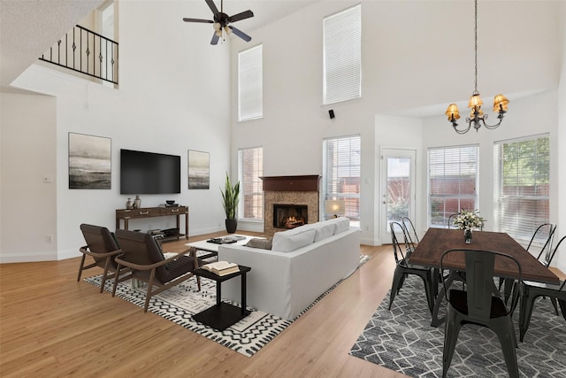 1084 Leisure Ln, Irving, TX 75063 - living room featuring a high ceiling, a lit fireplace, wood finished floors, a chandelier, and a ceiling fan