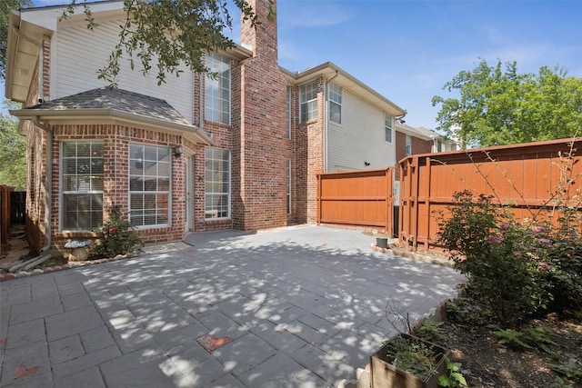 1084 Leisure Ln, Irving, TX 75063 - rear view of property featuring a chimney, brick siding, a patio area, and a gate