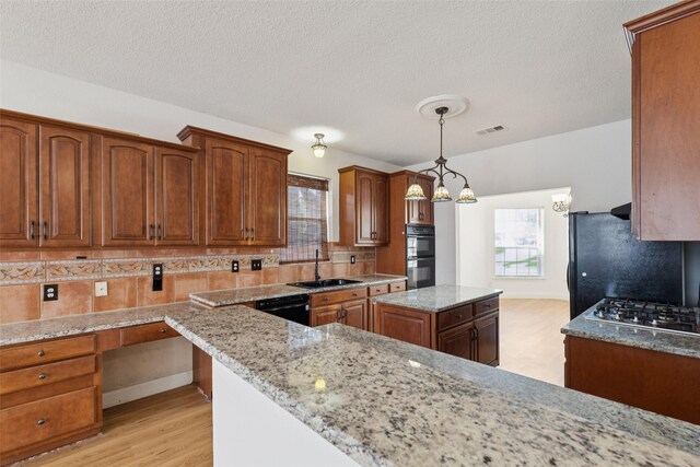 1084 Leisure Ln, Irving, TX 75063 - kitchen featuring black appliances, a kitchen island, light stone countertops, tasteful backsplash, and hanging light fixtures