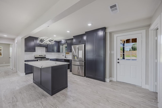 703 E Center St E, Duncanville, TX 75116 - kitchen featuring stainless steel appliances, a chandelier, a center island, light stone countertops, and baseboards
