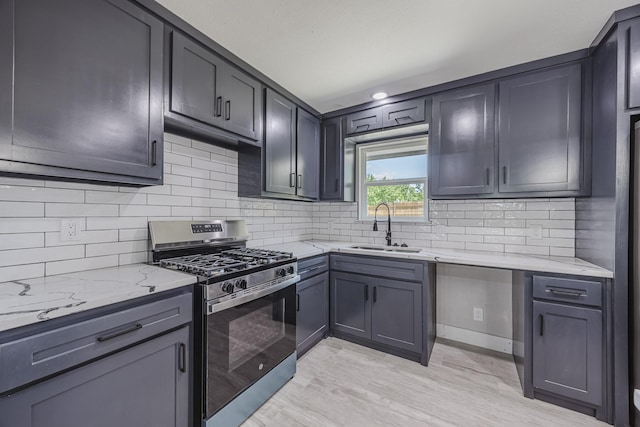 703 E Center St E, Duncanville, TX 75116 - kitchen featuring stainless steel range with gas stovetop, a sink, light stone countertops, decorative backsplash, and light wood-type flooring