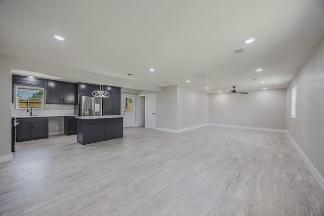 703 E Center St E, Duncanville, TX 75116 - kitchen featuring stainless steel fridge, a center island, a sink, open floor plan, and decorative backsplash