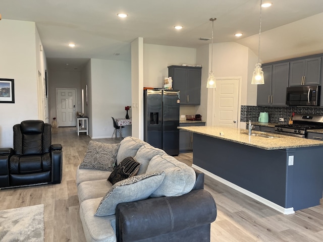 1311 Rosler St, Mansfield, TX 76063 - kitchen with appliances with stainless steel finishes, open floor plan, a sink, light stone counters, and light wood-type flooring