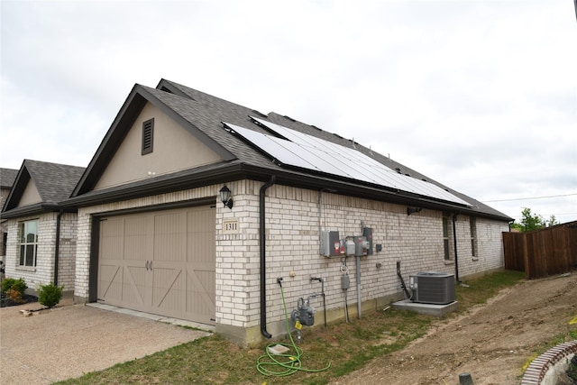 1311 Rosler St, Mansfield, TX 76063 - view of home's exterior featuring an attached garage, roof mounted solar panels, central AC unit, driveway, and a shingled roof