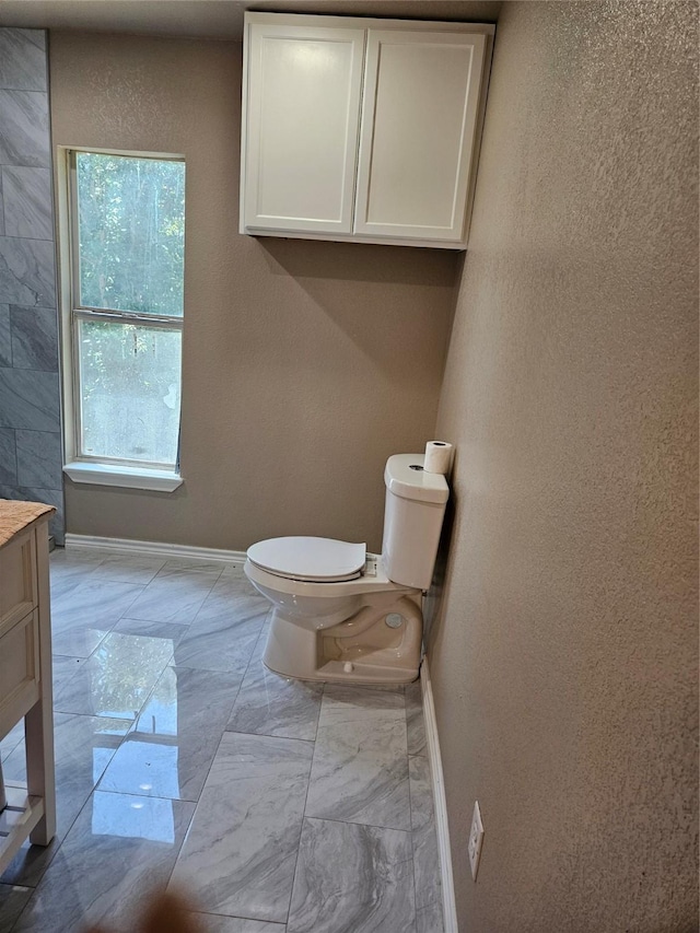 5301 Bonnell Ave, Fort Worth, TX 76107 - bathroom featuring baseboards, toilet, marble finish floors, vanity, and a textured wall