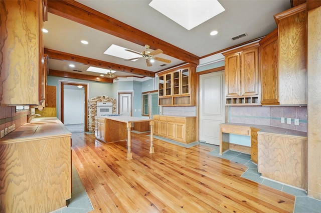 661 Diamond Point Dr, Oak Point, TX 75068 - kitchen featuring a skylight, light wood finished floors, beam ceiling, recessed lighting, and decorative backsplash
