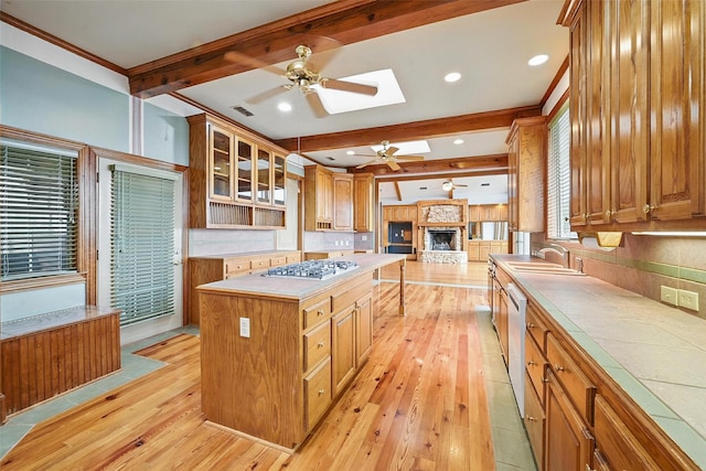 661 Diamond Point Dr, Oak Point, TX 75068 - kitchen featuring a ceiling fan, stainless steel appliances, light wood-type flooring, beamed ceiling, and a fireplace