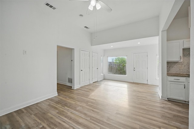 710 W Owing St, Denison, TX 75020 - unfurnished living room with light wood-style floors, a ceiling fan, recessed lighting, and a towering ceiling
