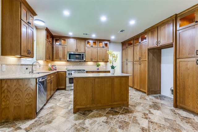 206 Crooked Creek Dr, Richardson, TX 75080 - kitchen featuring appliances with stainless steel finishes, backsplash, light stone finish floors, a kitchen island, and light stone counters
