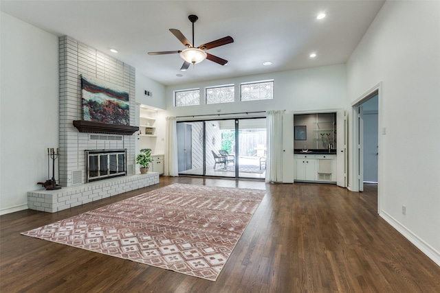 206 Crooked Creek Dr, Richardson, TX 75080 - unfurnished living room featuring a ceiling fan, wood finished floors, a fireplace, a towering ceiling, and recessed lighting