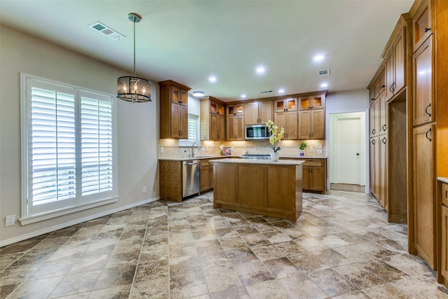 206 Crooked Creek Dr, Richardson, TX 75080 - kitchen with appliances with stainless steel finishes, brown cabinets, decorative backsplash, light stone finish flooring, and recessed lighting