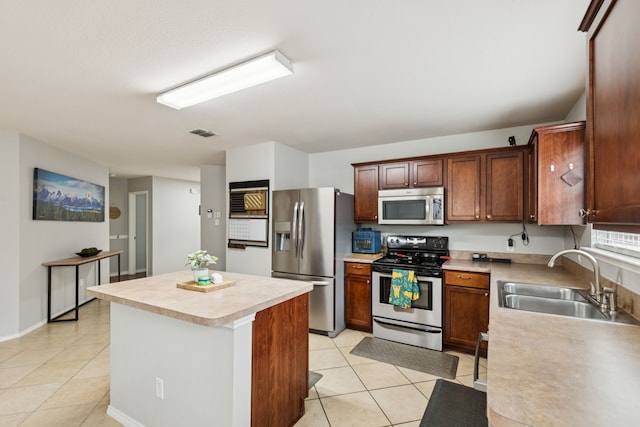 8824 Wagon Trl, Cross Roads, TX 76227 - kitchen featuring appliances with stainless steel finishes, a sink, light tile patterned floors, a center island, and light countertops