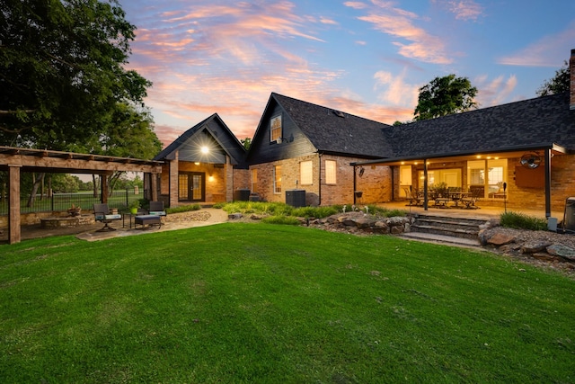 990 Cornelius Rd, Rockwall, TX 75087 - back of house at dusk featuring a patio, a yard, brick siding, and central AC unit
