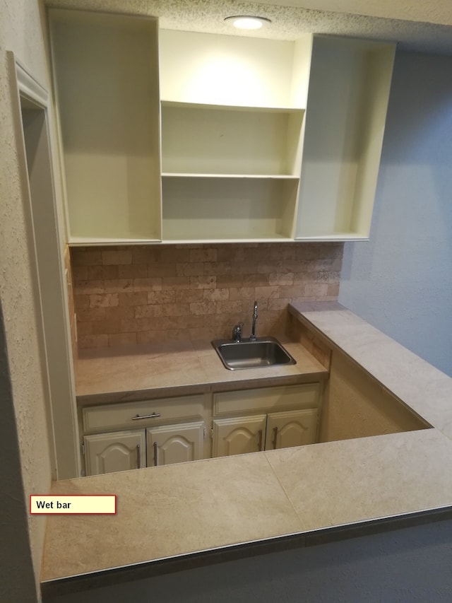 1211 Oriental Ave, Arlington, TX 76011 - kitchen featuring a sink, open shelves, backsplash, light countertops, and a textured ceiling