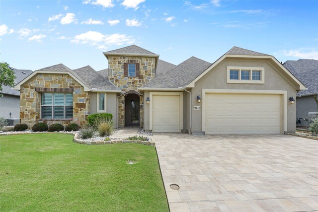 9921 Flint Way, Denton, TX 76207 - view of front of home with stone siding, stucco siding, a front yard, a garage, and decorative driveway