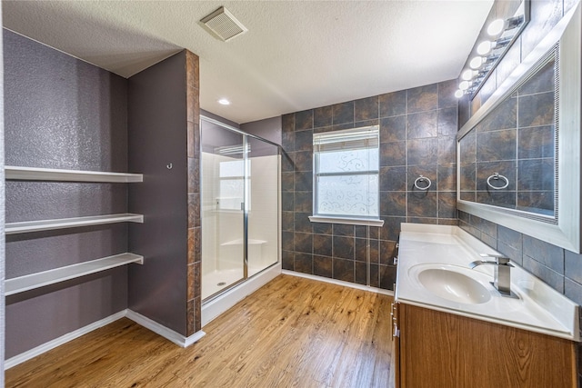 4026 Red Rock Dr, Heartland, TX 75126 - bathroom featuring tile walls, a shower stall, vanity, wood finished floors, and a textured ceiling