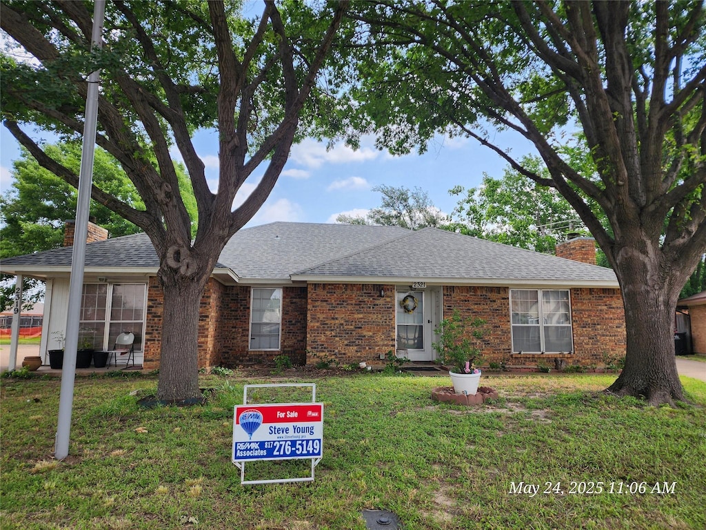 2321 Lido Ln, Arlington, TX 76015 - view of front facade with a chimney, a front lawn, brick siding, and roof with shingles