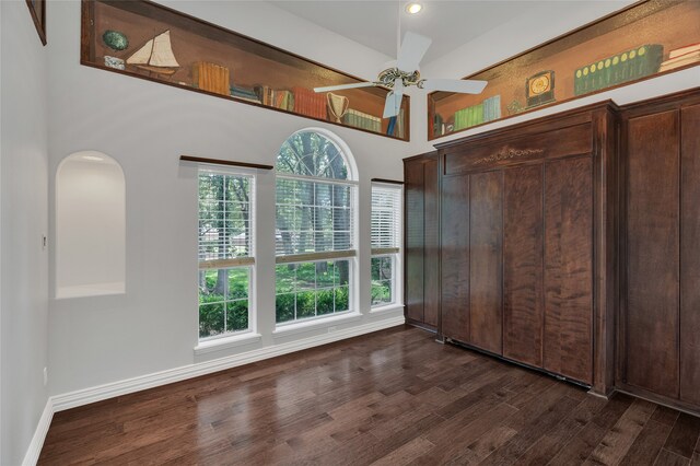 732 Richmond Ln, Keller, TX 76248 - unfurnished bedroom with dark wood-style flooring, arched walkways, multiple windows, a towering ceiling, and baseboards