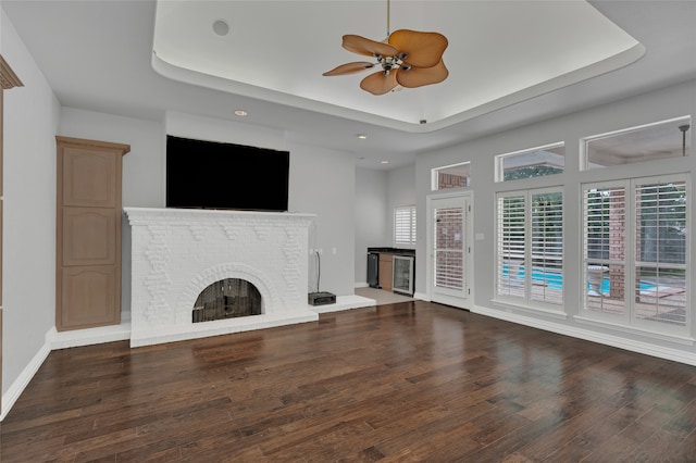 732 Richmond Ln, Keller, TX 76248 - unfurnished living room featuring a tray ceiling, a brick fireplace, wood finished floors, a ceiling fan, and recessed lighting
