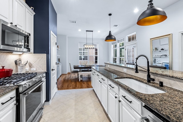 15763 Spectrum Dr Unit 93, Addison, TX 75001 - kitchen with stainless steel appliances, a sink, white cabinetry, hanging light fixtures, and backsplash