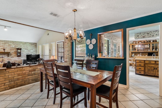 13103 Halwin Cir, Dallas, TX 75243 - dining room with a textured ceiling, light tile patterned flooring, a chandelier, and brick wall