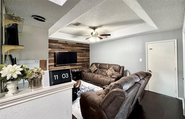 629 Yosemite Trl, Mesquite, TX 75149 - living area featuring a textured ceiling, a tray ceiling, a ceiling fan, wood walls, and wood finished floors