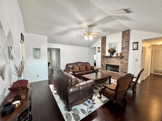 629 Yosemite Trl, Mesquite, TX 75149 - living room featuring vaulted ceiling, dark wood-style flooring, ceiling fan, a fireplace, and a textured ceiling