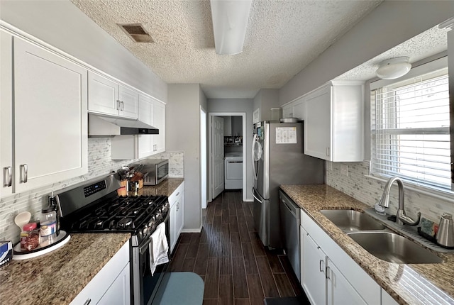 629 Yosemite Trl, Mesquite, TX 75149 - kitchen featuring stainless steel appliances, under cabinet range hood, washer / clothes dryer, a sink, and white cabinetry