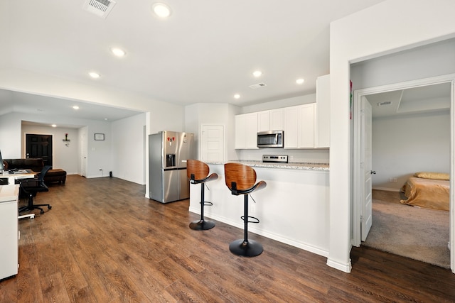 105 Musgrove Rd, Everman, TX 76140 - kitchen featuring stainless steel appliances, white cabinets, dark wood-style floors, recessed lighting, and a kitchen breakfast bar