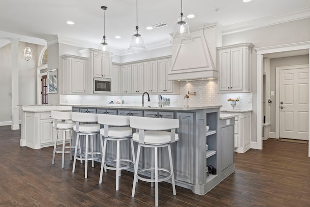 220 Sunray Ln, Sunnyvale, TX 75182 - kitchen with stainless steel microwave, a center island with sink, backsplash, dark wood-type flooring, and white cabinetry