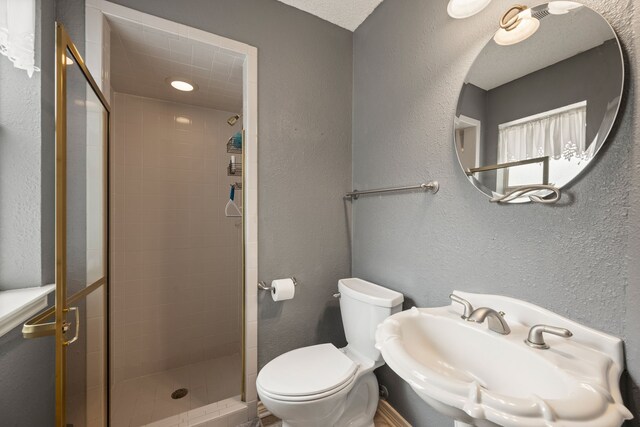 6604 Nantucket Ln, Arlington, TX 76001 - full bathroom featuring a stall shower, toilet, a sink, and a textured wall