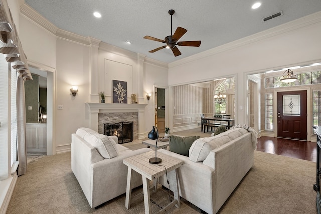 6604 Nantucket Ln, Arlington, TX 76001 - carpeted living area with ornamental molding, a stone fireplace, a decorative wall, a ceiling fan, and a chandelier