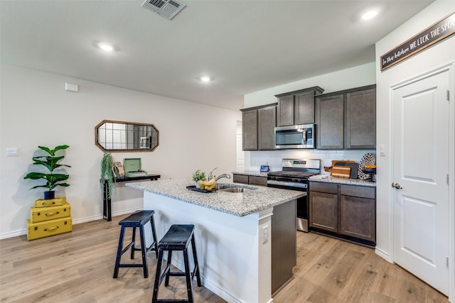 708 Cool Canyon Trl, Princeton, TX 75407 - kitchen with stainless steel appliances, dark brown cabinets, light wood-type flooring, light stone countertops, and recessed lighting