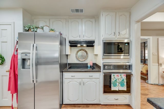 233 Shields Dr, Trophy Club, TX 76262 - kitchen featuring black appliances, under cabinet range hood, dark countertops, light wood-style flooring, and white cabinets